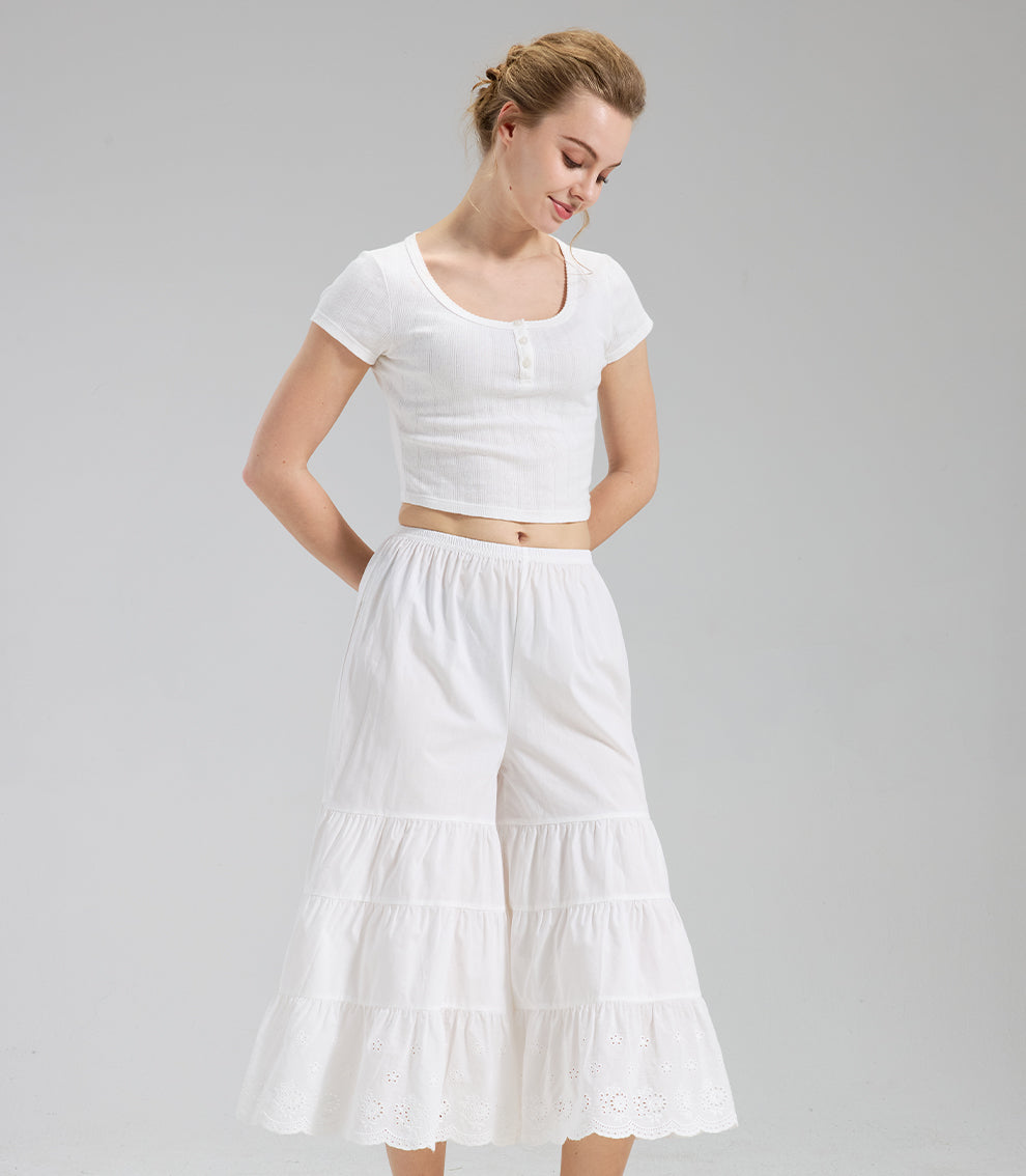 Model wearing ivory vintage cottagecore pants with tiered ruffles and eyelet lace for a feminine look.