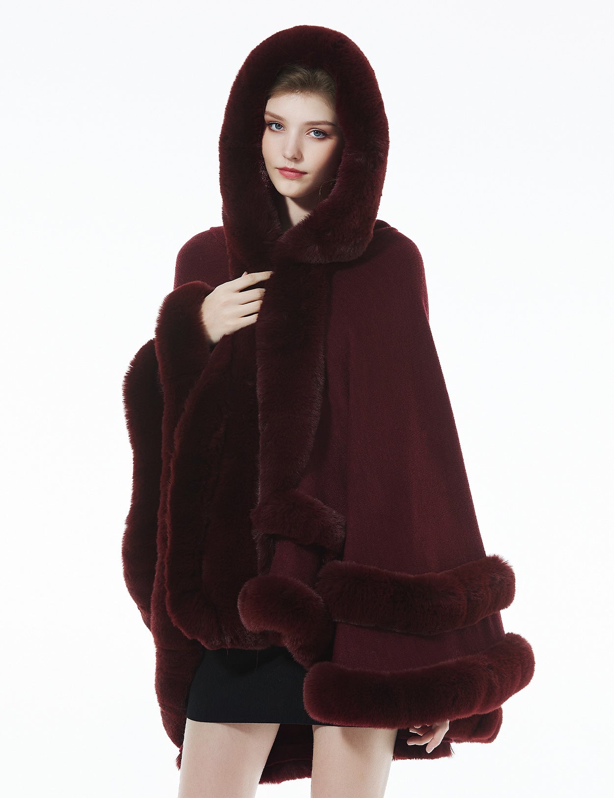 Model in burgundy hooded knit cape with hood up - rich color and faux fur creating luxurious winter look