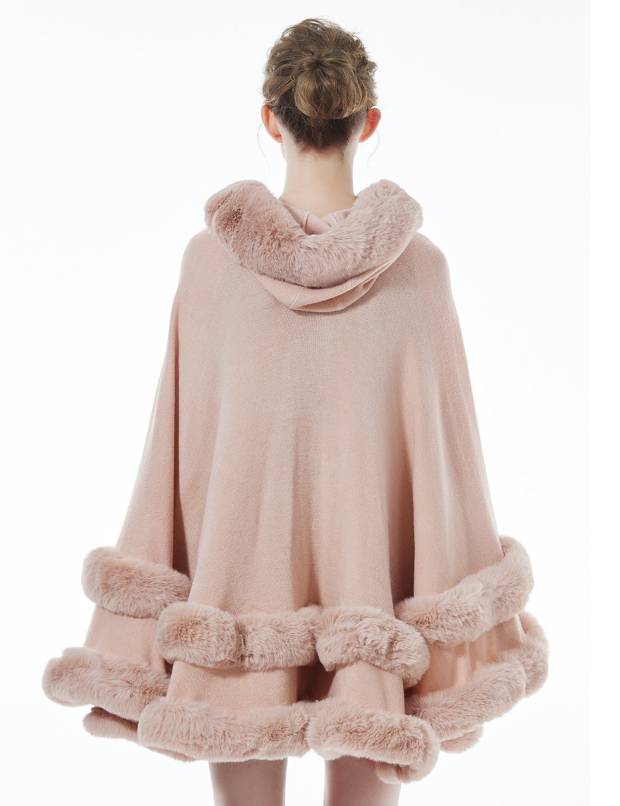 Back view of pink hooded knit cape displaying flowing silhouette and faux fur hood detail