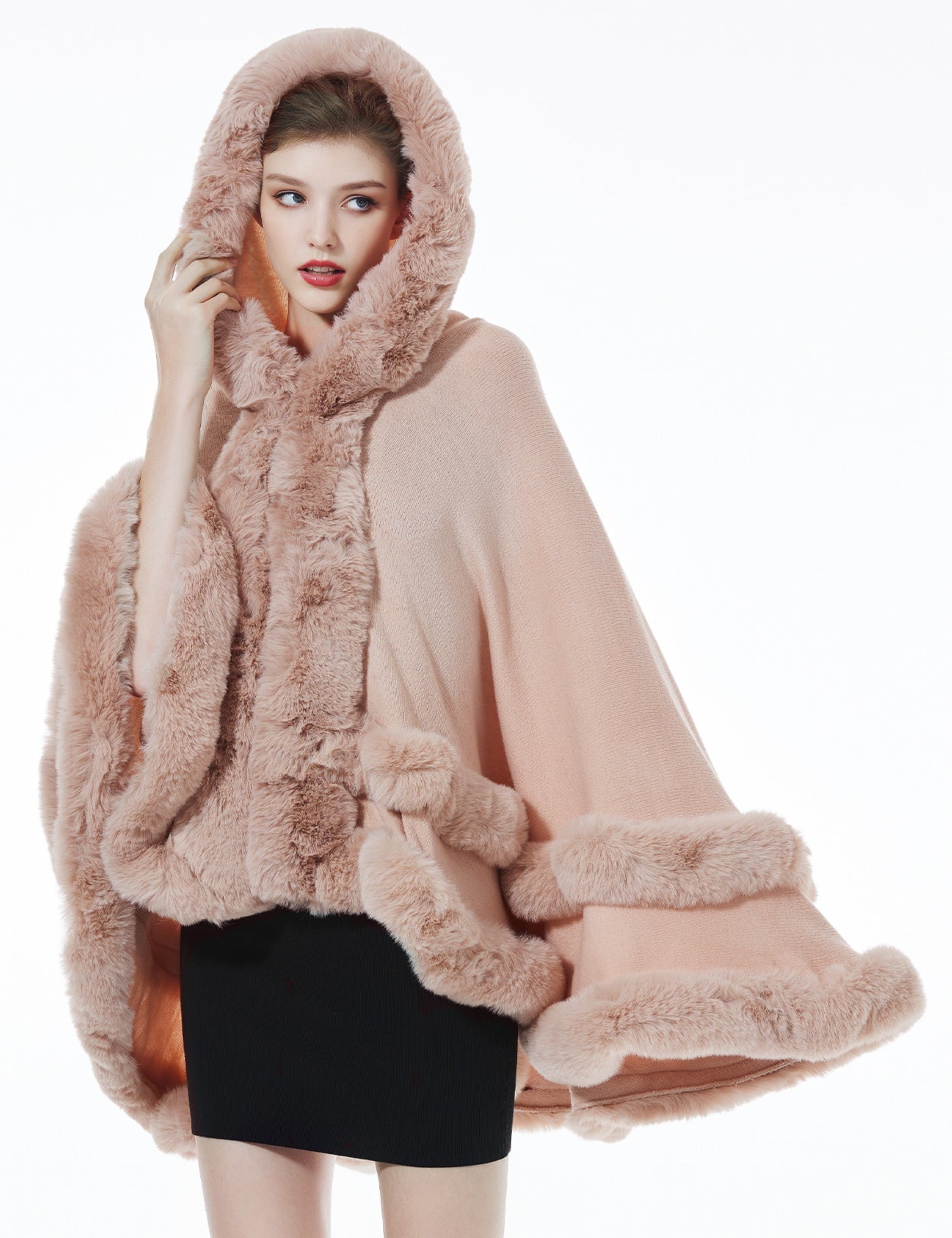 Detailed close-up of pink knit cape's oversized hood with luxurious faux fur lining